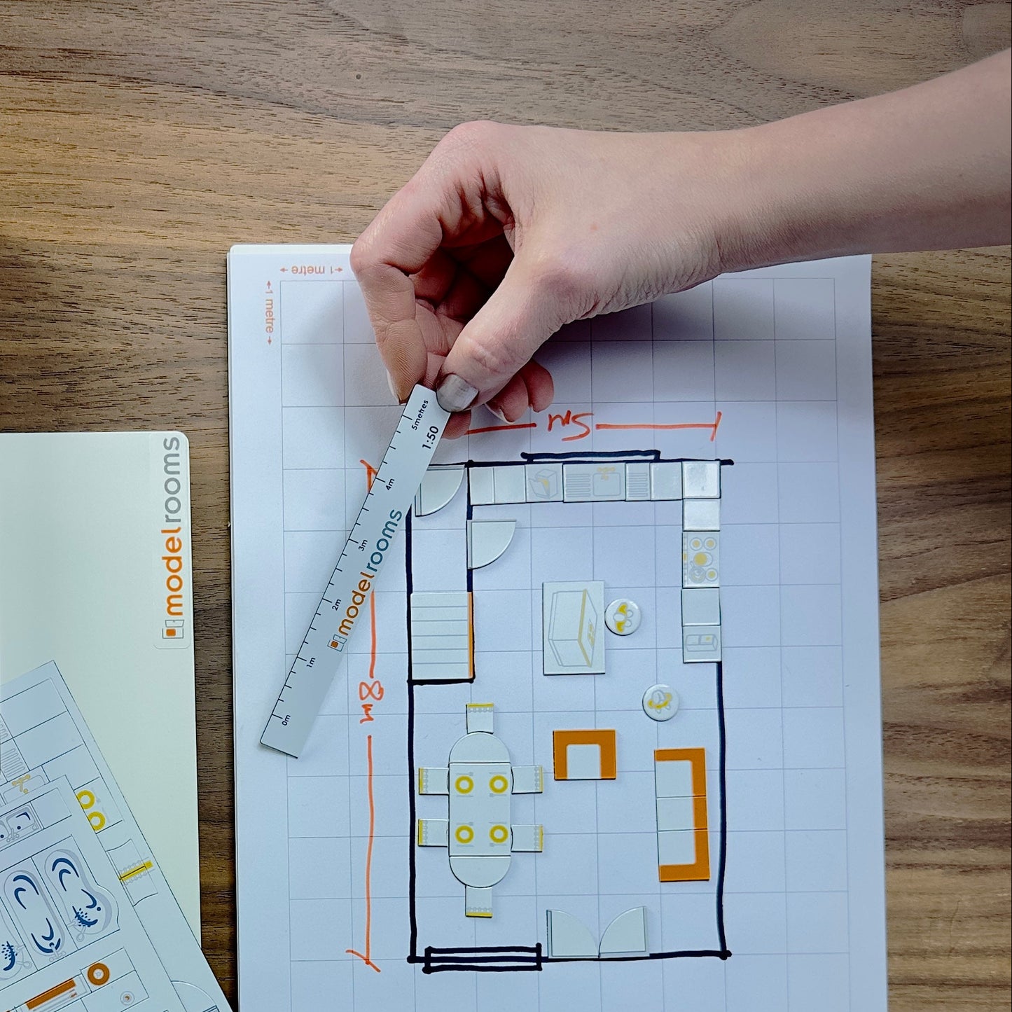 Person working on a floor plan with model rooms branding on a wooden table